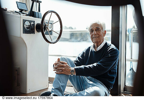 Smiling senior man sitting by window at houseboat