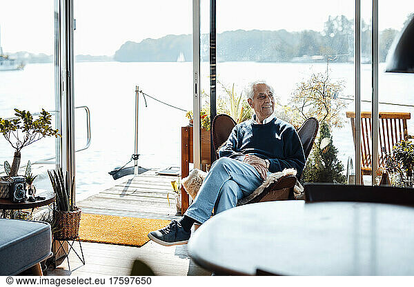 Smiling senior man sitting on chair at houseboat