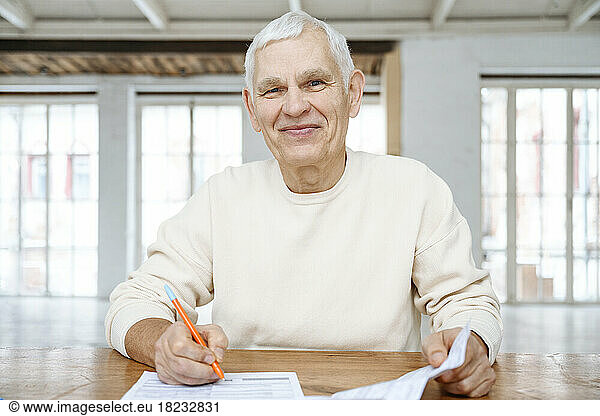 Smiling senior man with financial bills at home