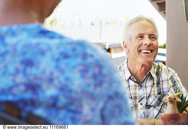 Smiling senior man with grey hair sitting outdoors.