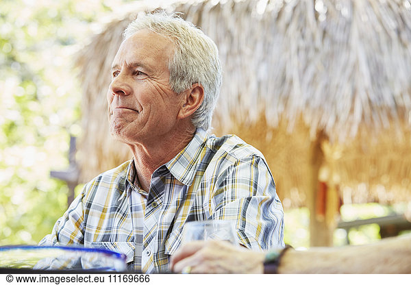 Smiling senior man with grey hair sitting outdoors.