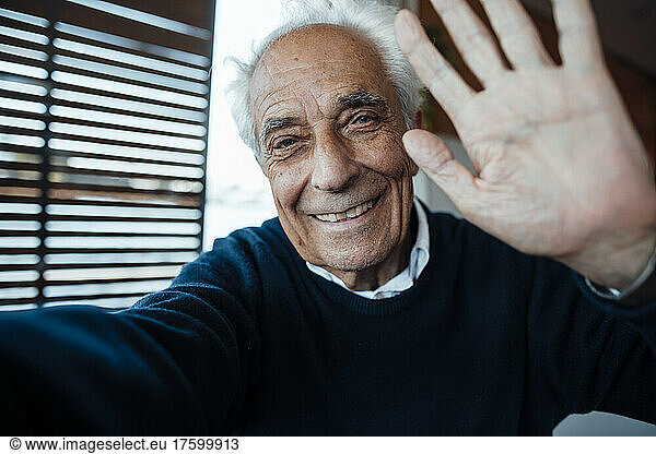 Smiling senior man with white hair gesturing at houseboat