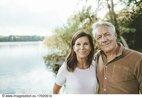 Smiling senior man with woman standing by lake