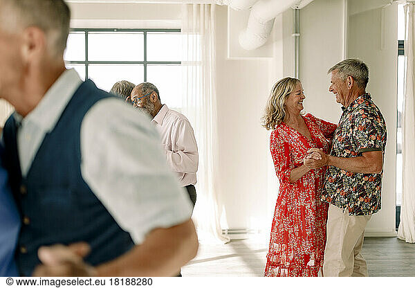Smiling senior men and woman dancing together in class