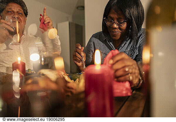 Smiling senior woman having food with candles on table at home