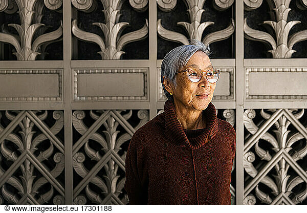 Smiling Senior Woman looking away against ornate city gate background