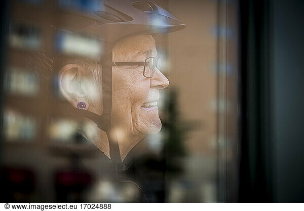 Smiling senior woman seen through window at home