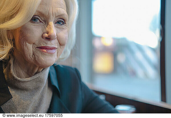 Smiling senior woman sitting by window at cafe