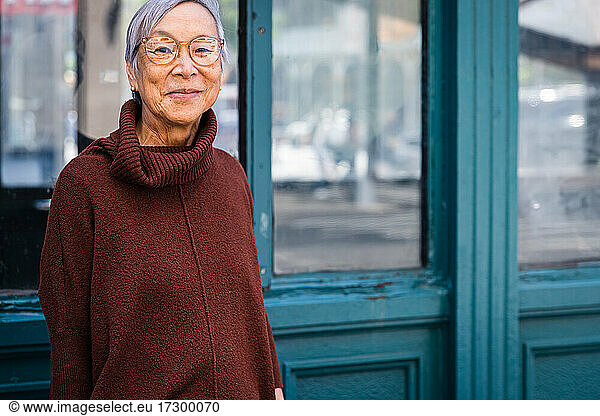 Smiling senior woman wearing glasses in urban city environment