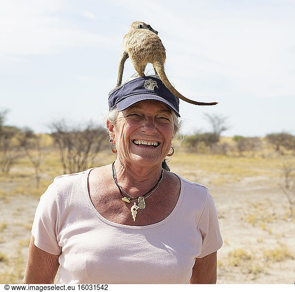 smiling senior woman with Meerkat on her head  Kalahari Desert  Makgadikgadi Salt Pans  Botswana