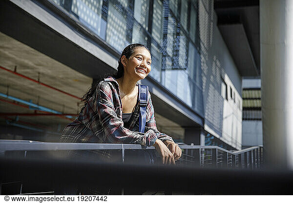 Smiling student standing near university railing