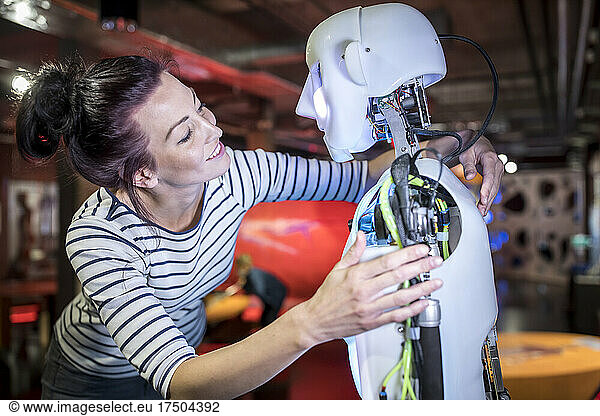 Smiling technician with arm around human robot at workshop
