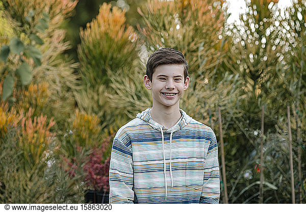 Smiling teen boy with braces in blue striped hoodie outdoors
