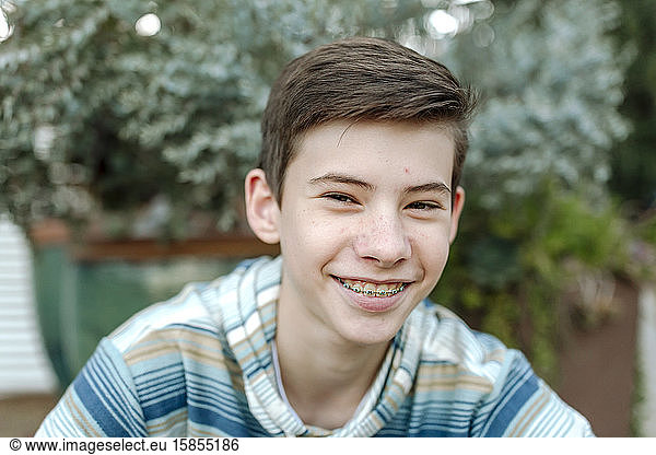 Smiling teenage boy with braces wearing blue striped shirt