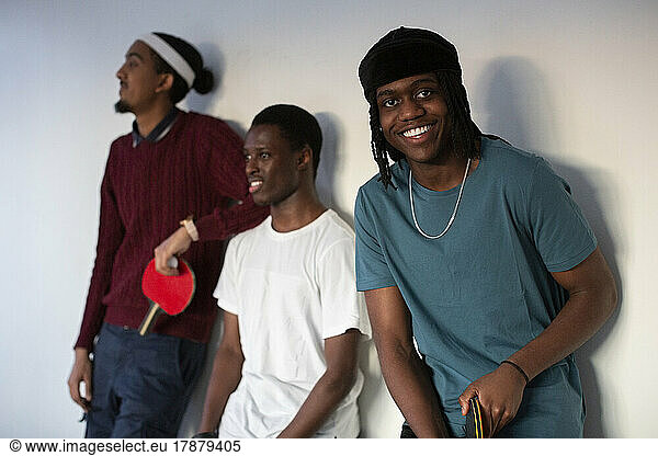 Smiling teenage boy with friends against wall in games room