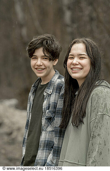 Smiling teenage siblings in casuals on rainy day