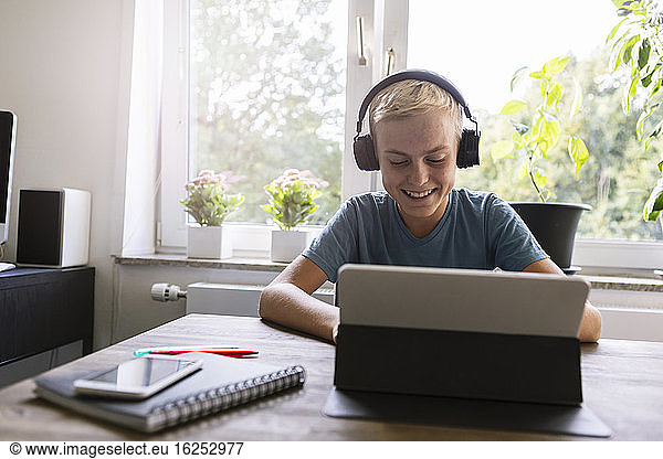 Smiling teenager using laptop at home