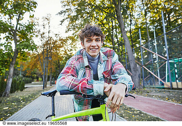smiling teenager with a bicycle in the park