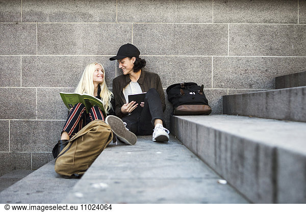 Smiling teenagers sitting on steps and looking face to face