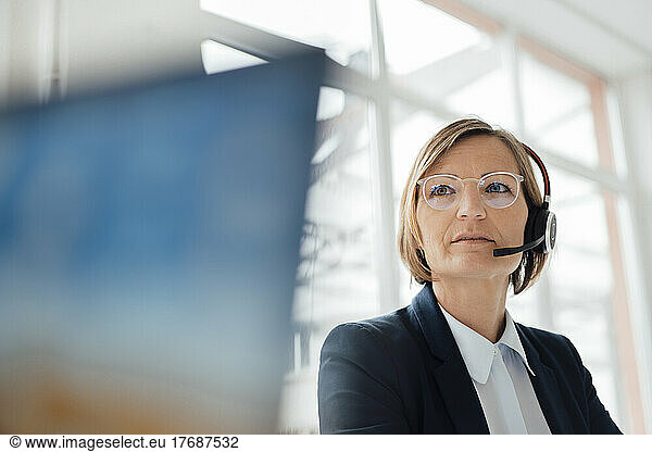 Smiling telecaller wearing headset sitting in office