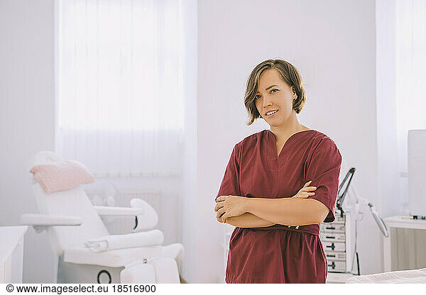 Smiling therapist standing with arms crossed in salon