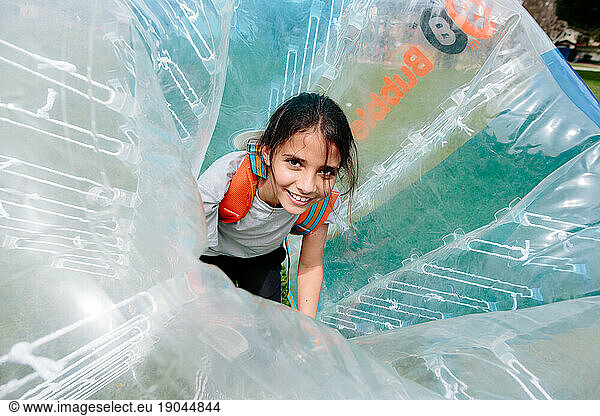 Smiling tween girl is strapped into an inflatable ball