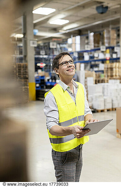 Smiling warehouse worker with tablet PC working in warehouse