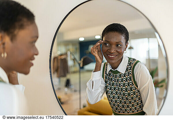 Smiling woman admiring herself in mirror at home