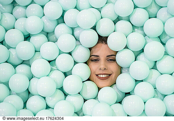 Smiling woman amidst blue balls