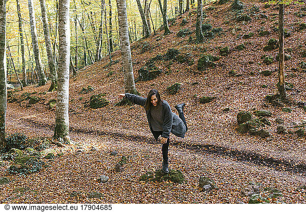 Smiling woman balancing on rock at Fageda D'en Jorda  Olot  Girona  Spain