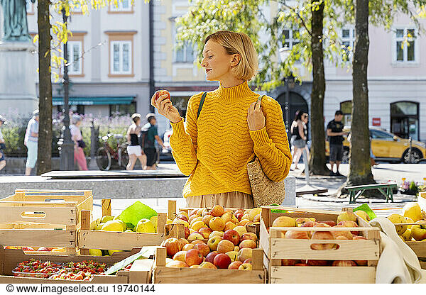 Smiling woman buying apples at farmer's market