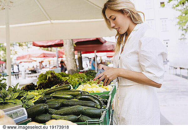 Smiling woman buying fresh vegetables in farmer's market