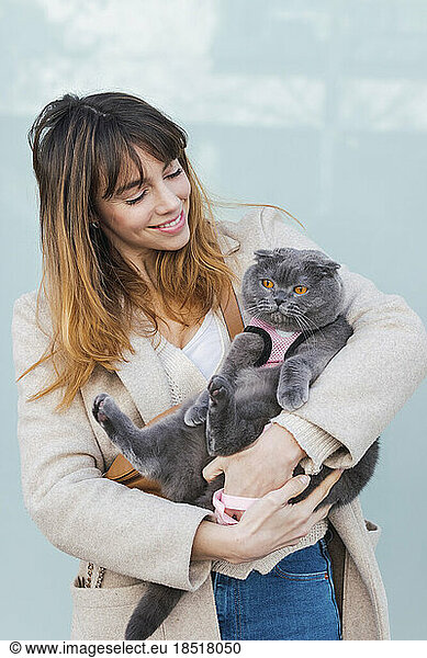 Smiling woman carrying gray cat