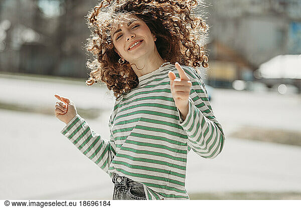 Smiling woman dancing and gesturing at sunny day