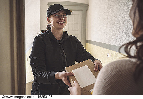 Smiling woman delivering package to customer at doorstep