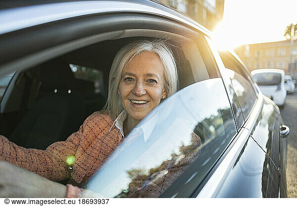 Smiling woman driving car at sunny day