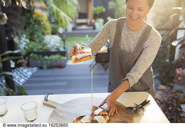 Smiling woman eating homemade pizza on patio