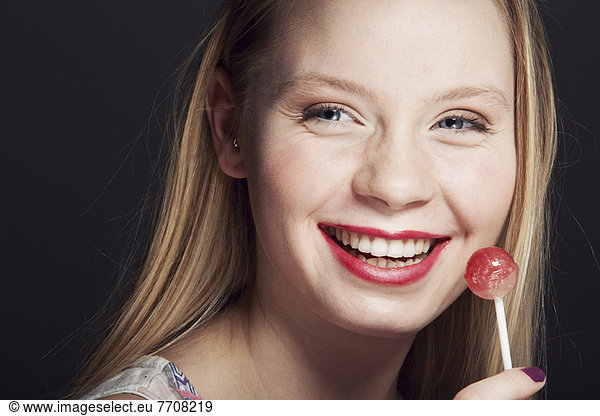 Smiling woman eating lollipop