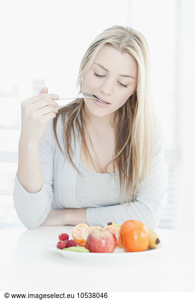 Smiling woman eating plate of fruit