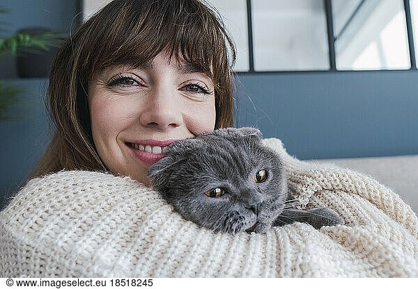 Smiling woman embracing cat at home