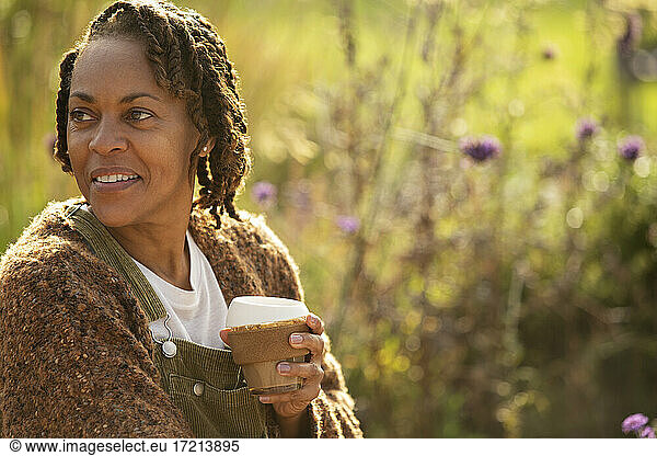 Smiling woman enjoying coffee in sunny garden