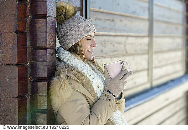Smiling woman enjoying coffee in winter holidays