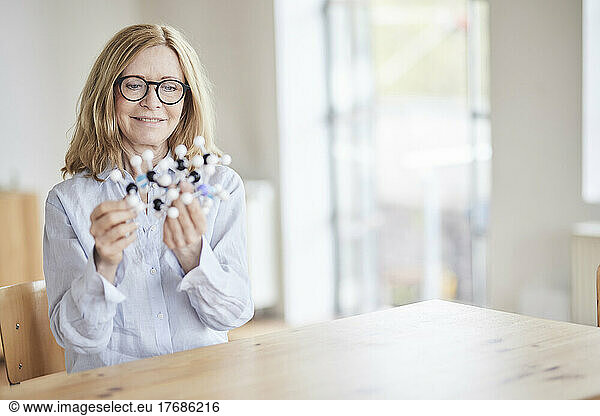 Smiling woman examining molecular structure at table