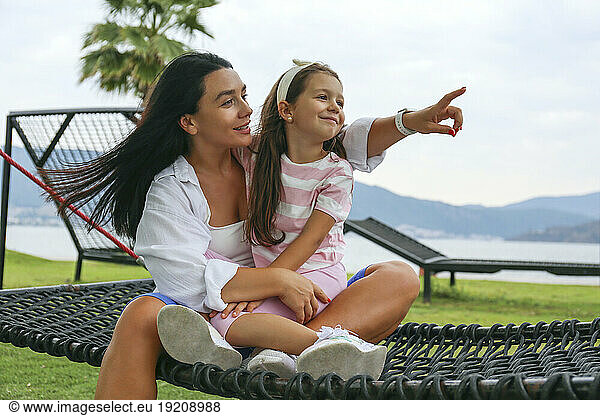 Smiling woman gesturing with mother sitting on hammock