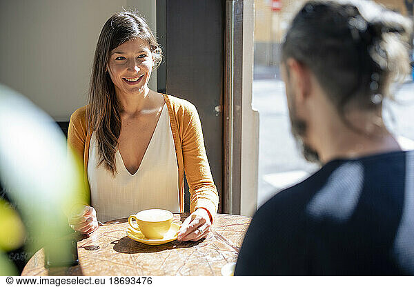 Smiling woman having coffee with man at cafe