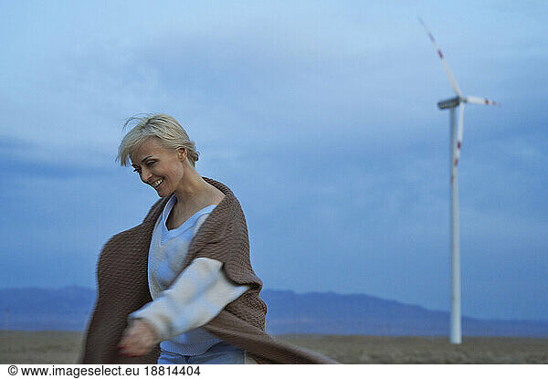 Smiling woman having fun near wind turbines in desert
