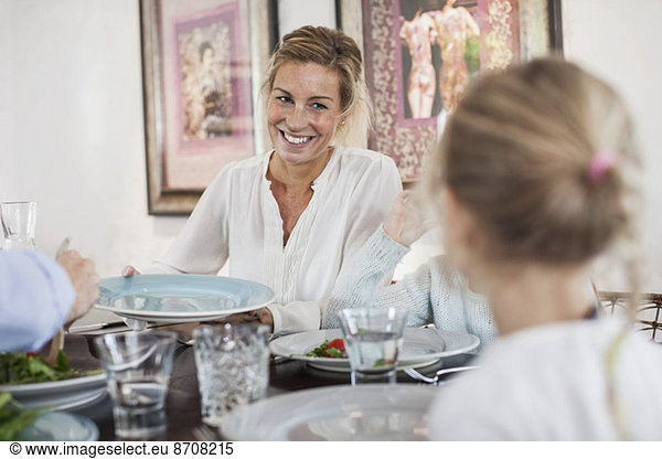 Smiling woman having lunch with family at dining table