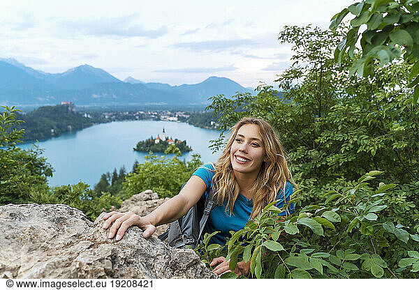 Smiling woman hiking over rocks amidst plants