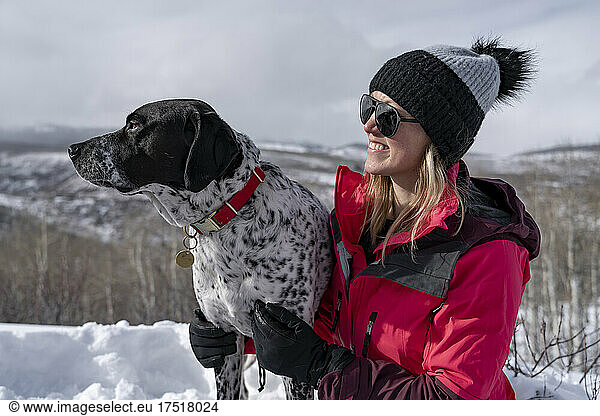Smiling woman hiking with dog during winter vacation