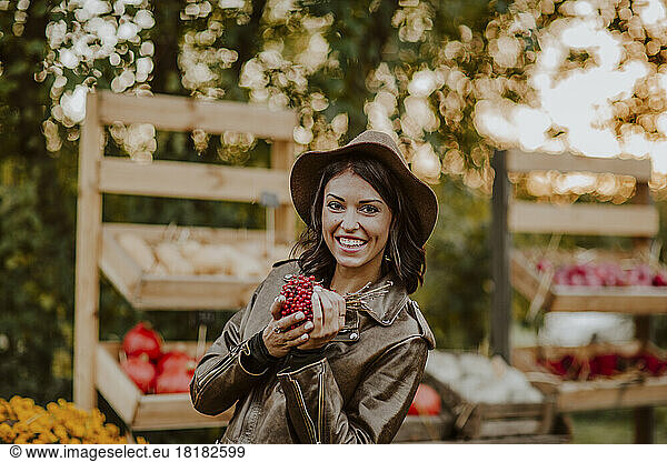 Smiling woman holding berry fruits at market